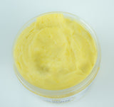 Pot ouvert de chantilly de karité fouettée, texture légère et onctueuse, vue en gros plan sur fond naturel. Mélange crémeux aux reflets beiges, évoquant la douceur des beurres d’Afrique.