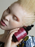 Femme albinos nattes collées noire tient shampoing cheveux secs crépus bouclés texturés argile rose doux hydratant routine capillaire Afro clay roses